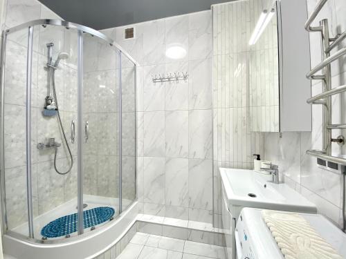 een witte badkamer met een douche en een wastafel bij Затишна і тепла квартира, метро Лівобережна, МВЦ, Інститут Серця in Kiev