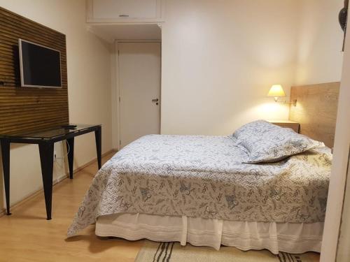 a bedroom with a bed and a desk and a television at KIKO in Tramandaí