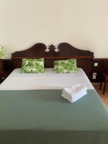 1 cama con cabecero de madera y almohadas verdes en Olivera Studio P&V Ste luce en Sainte-Luce