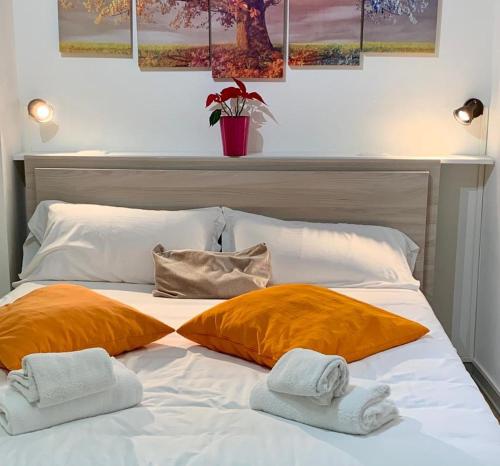 a bed with two orange pillows and towels on it at Tourist House Bologna Pratellino - Self Check-in in Bologna