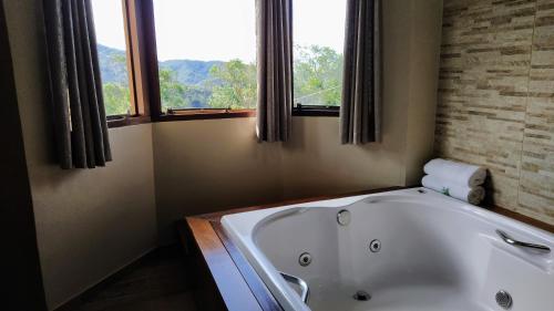 a bath tub in a bathroom with a window at Pousada Amor Perfeito in Visconde De Maua