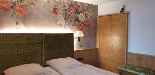 a bedroom with a bed and a wall with flowers at Haus Zauner in Reit im Winkl