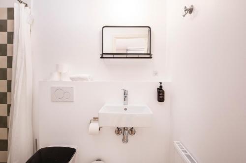 a white bathroom with a sink and a mirror at The Townhouse by Daniel&Jacob's in Copenhagen
