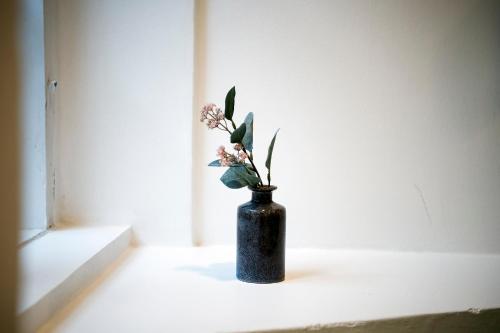 a black vase with flowers sitting on a window sill at The Townhouse by Daniel&Jacob's in Copenhagen