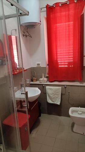a bathroom with a red shower curtain and a toilet at LA FINESTRA SUL MARE PIANO Terra in Trappeto