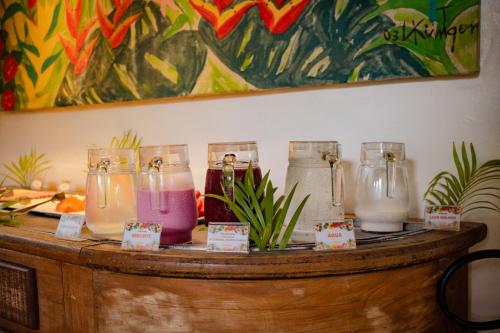 a table with four glass jars with different colored liquids at Pousada Vira Canoa in Itacaré