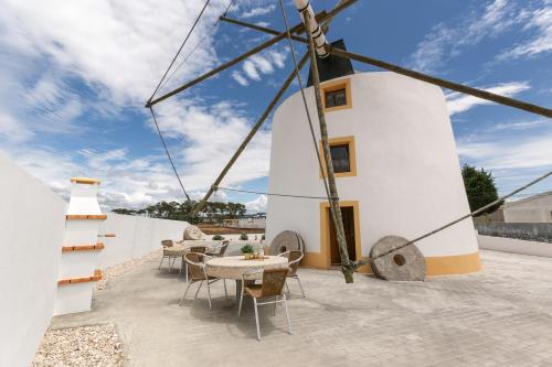 a windmill on the roof of a house with tables and chairs at Moinho do Sr. Arnaldo in Atouguia da Baleia