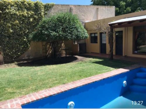 una casa con una piscina azul frente a un patio en Casa El Cobijo en Tandil