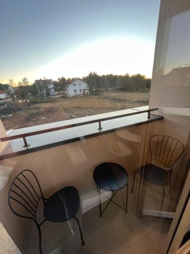 - deux chaises et une fenêtre avec vue sur une maison dans l'établissement Apartman Krčmar Divcibare, à Divčibare