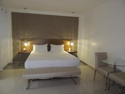 a bedroom with a large white bed and a table at Star Hotel in Itaperuna