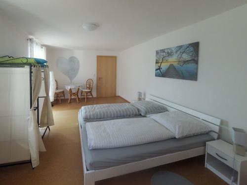 a white bedroom with a bed and a table at Ferienwohnung im bayerischen Wald in Tittling