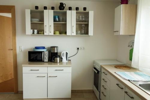 a kitchen with white cabinets and a microwave at Ferienwohnung im bayerischen Wald in Tittling