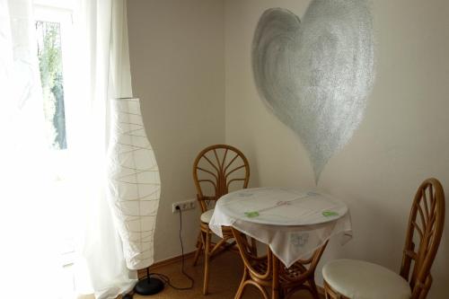 a table and chairs with a heart on the wall at Ferienwohnung im bayerischen Wald in Tittling
