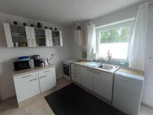 a kitchen with white cabinets and a sink and a window at Ferienwohnung im bayerischen Wald in Tittling