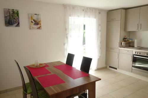 a kitchen with a wooden table with red mats on it at Ferienwohnung im bayerischen Wald in Tittling