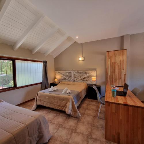 a hotel room with two beds and a desk at Apartamentos Andrea in Villa General Belgrano