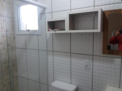 a bathroom with a toilet and a window and a person taking a picture at Casa em Torres Praia da Cal in Torres