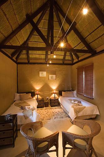 Windhoek Noord的住宿－Beenbreck Guest Farm，一间设有两张床和一张桌子及椅子的房间