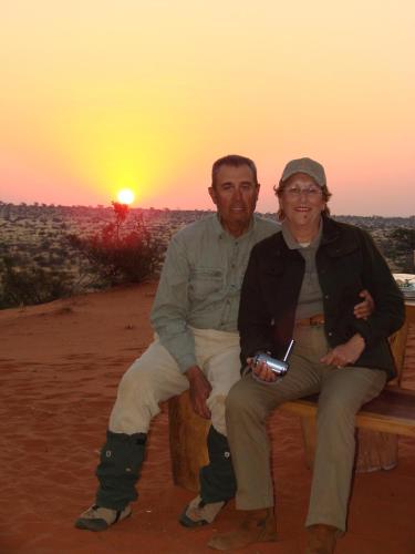 two men sitting on a bench in front of the sunset at Beenbreck Guest Farm in Klein Nauas