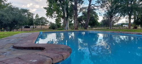 a swimming pool with blue water in a yard at Beenbreck Guest Farm in Windhoek Noord