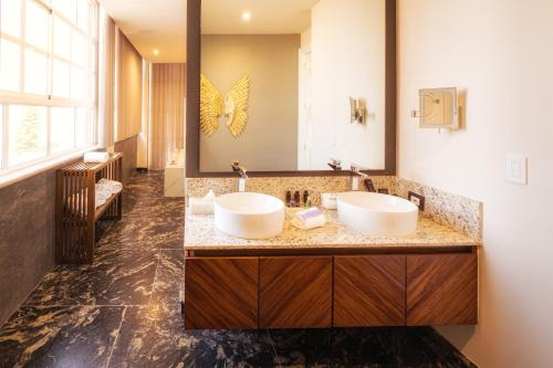 a bathroom with two sinks and a large mirror at HOTEL & SPA MANSION SOLIS by HOTSSON in Morelia