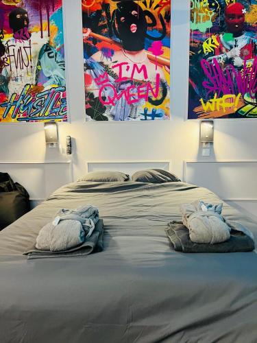 une chambre avec un lit avec deux serviettes dessus dans l'établissement Capsule Street Art - Sauna- Jacuzzi - Playstation 5 - Billard - Netflix - Home cinéma - Terrasse, à Douai