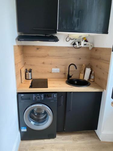 een kleine keuken met een wasmachine en een wastafel bij Le Cosy in Châteauroux