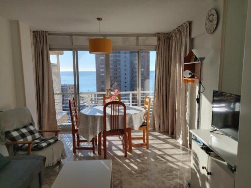 - un salon avec une table, des chaises et une grande fenêtre dans l'établissement Apartment caballos levante beach, à Benidorm