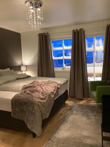 1 dormitorio con 1 cama, lámpara de araña y ventanas en Fantastic view, quiet and relaxing by the sea en Kvaløya