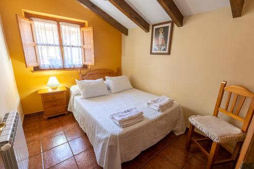 a bedroom with a bed and a chair and a window at Apartamentos Rurales Villa-García in Corigos