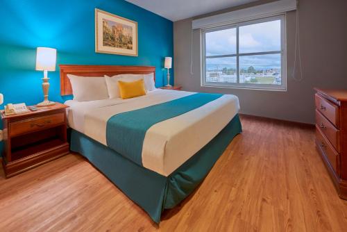 um quarto com uma cama grande e uma janela em Sierra Suites By HP Hotels em San Luis Potosí