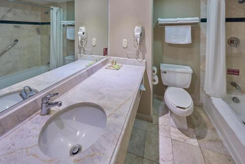 a bathroom with a sink and a toilet and a tub at Sierra Suites By HP Hotels in San Luis Potosí