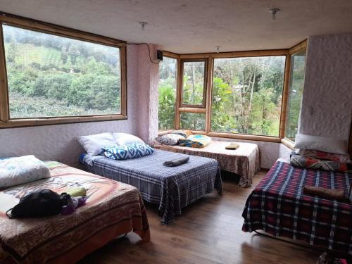 a room with two beds and a couch and windows at CASA JUANA DE ORO in Baños