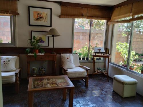 ein Wohnzimmer mit Stühlen, einem Tisch und Fenstern in der Unterkunft Tiempo de Paz in Guaymallen