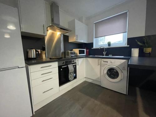 a kitchen with a washing machine and a washer at Dunbeth House in Coatbridge