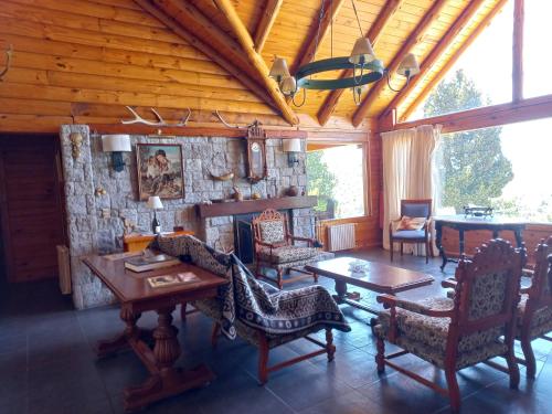 - un salon avec une table, des chaises et un mur en pierre dans l'établissement La Soñada casa de montaña, à San Martín de los Andes