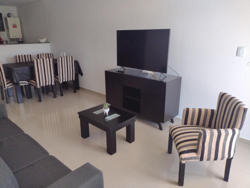sala de estar con TV, sillas y mesa en Departamento Caleta View en Puerto Madryn