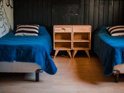 a room with two beds and a night stand with two beds at Hostel Like Quijote in San Carlos de Bariloche