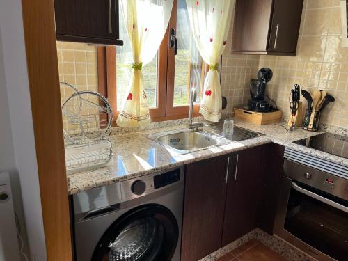 a kitchen with a sink and a washing machine at Alojamiento Rural El Morenal in Tragacete