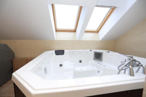 a large white bath tub in a bathroom with skylights at Ducatul Bucovinei in Mănăstirea Humorului