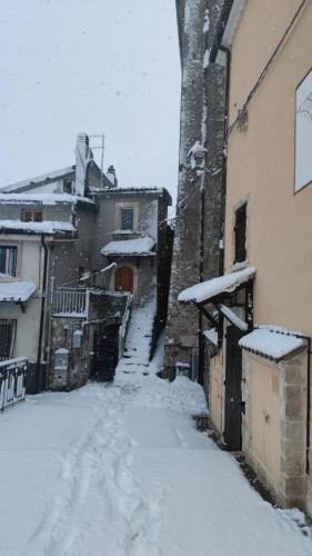 a snow covered alley with buildings and a house at Casa vacanze Rocca in Roccaraso