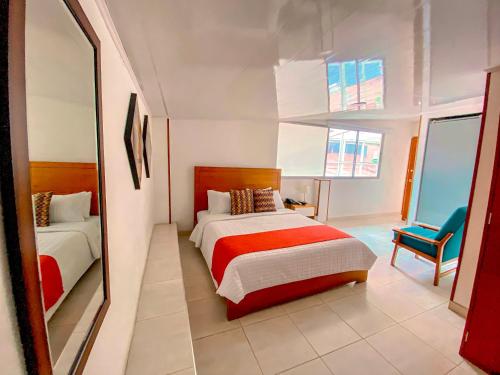 a bedroom with two beds and a mirror at Hotel Maceo Chico in Bogotá