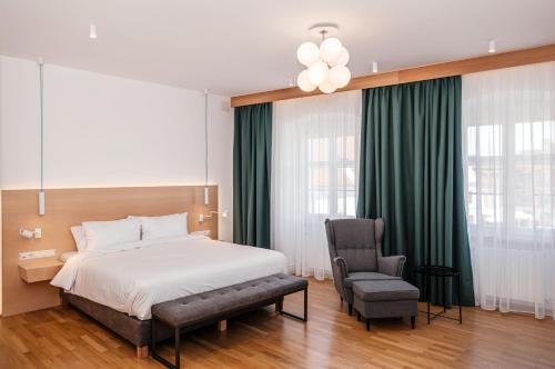 een slaapkamer met een bed en een stoel bij Hotel Casa Luxemburg- Newly Renovated in Sibiu