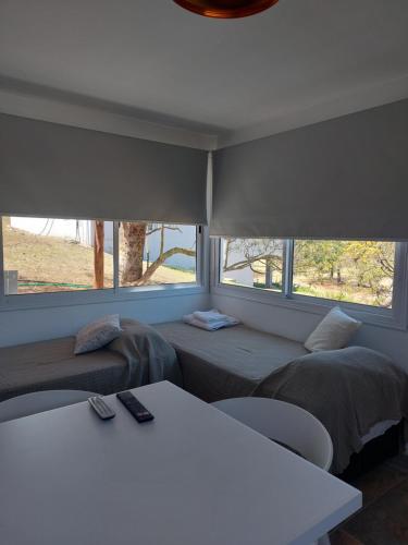 a room with two beds and a table and two windows at Altos del Monte in Villa Rumipal