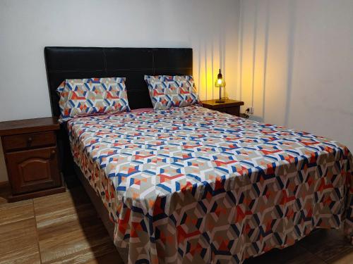 um quarto com uma cama grande e um edredão colorido em Casa de Toto 3 habitaciones em Puerto Iguazú