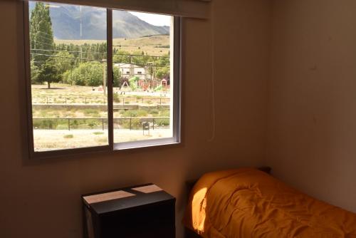 Un dormitorio con una cama y una ventana con vistas. en COMPLEJO LA CASCADA ESQUEL, en Esquel