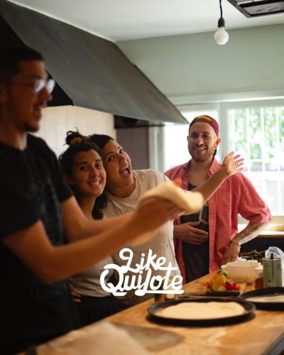 un grupo de personas de pie alrededor de una mesa en una cocina en Hostel Like Quijote en San Carlos de Bariloche