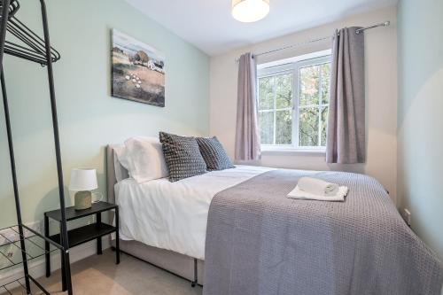 a bedroom with a bed and a window at Comfortable House close to Junction 15 of M1 in Northampton