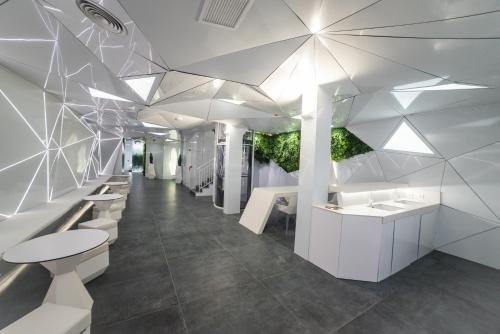 un vestíbulo con escritorios blancos y plantas en el techo en Optimi Rooms Madrid en Madrid