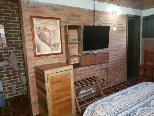 een slaapkamer met een bakstenen muur en een televisie bij Villa Nico hospedaje campestre in Bochalema